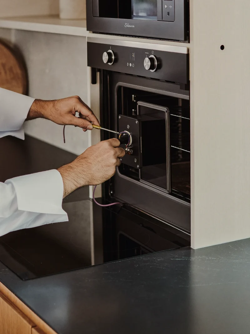 Forno con pannello di comando aperto accanto a un piano a induzione.